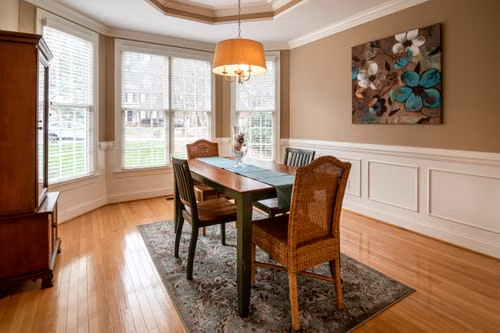 Custom crown molding and wainscoting in a Springfield, MO dining room with hardwood floors and a bay window