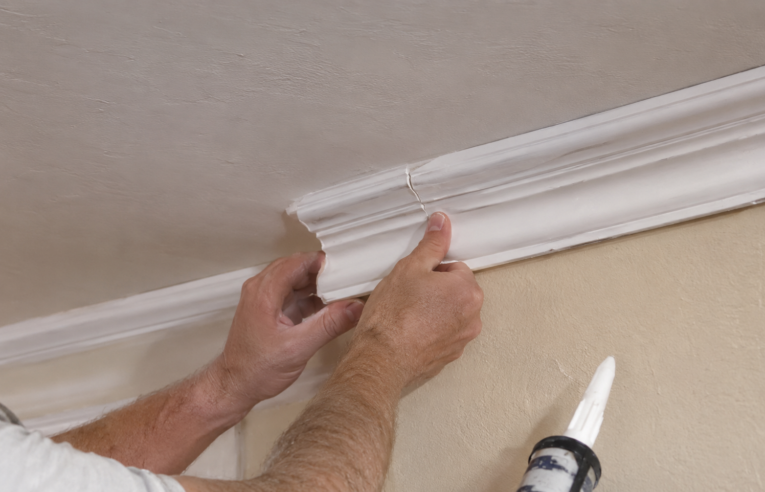 Carpenter hand-fitting a crown molding section during a crown molding repair in a Springfield, MO home
